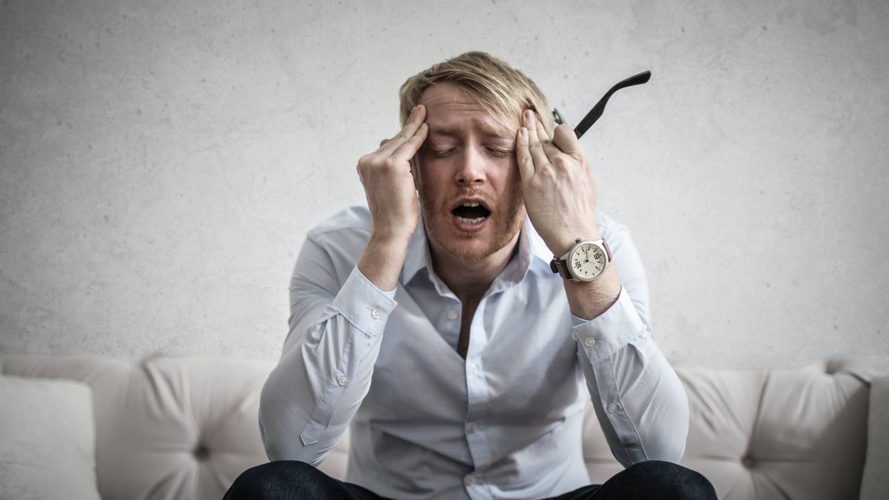 Imagem mostra homem branco com mãos na cabeça e expressão estressada.