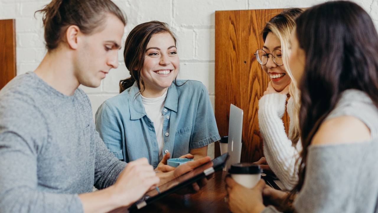 Quatro profissionais conversam ao redor de uma mesa e sorriem