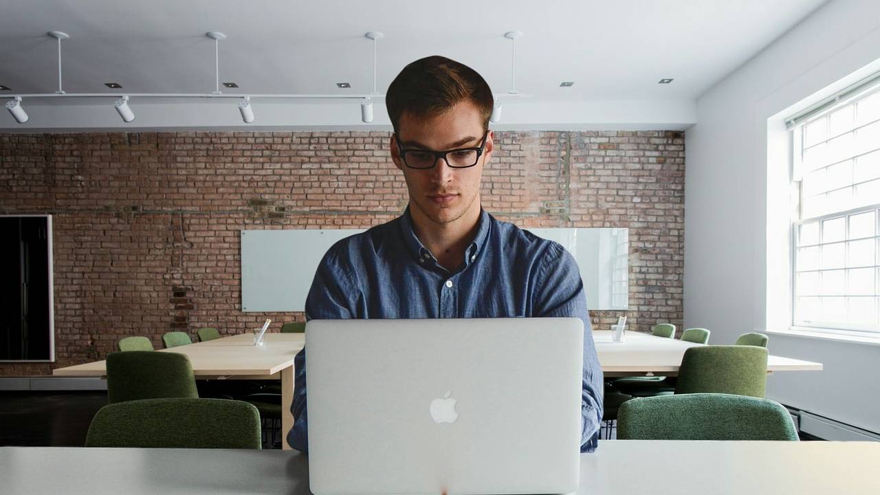 Um homem está concentrado olhando para a tela de um notebook.