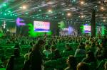 Um evento com diversas pessoas sentadas diante de um palco.