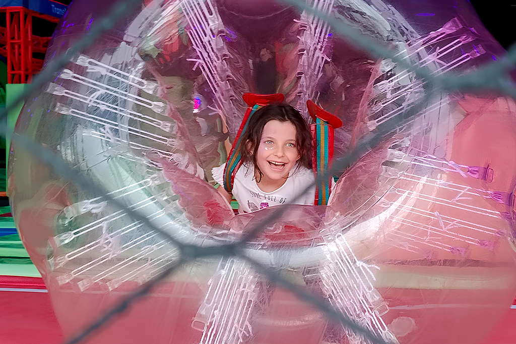 Foto de uma criança brincando dentro de uma bola inflável gigante.